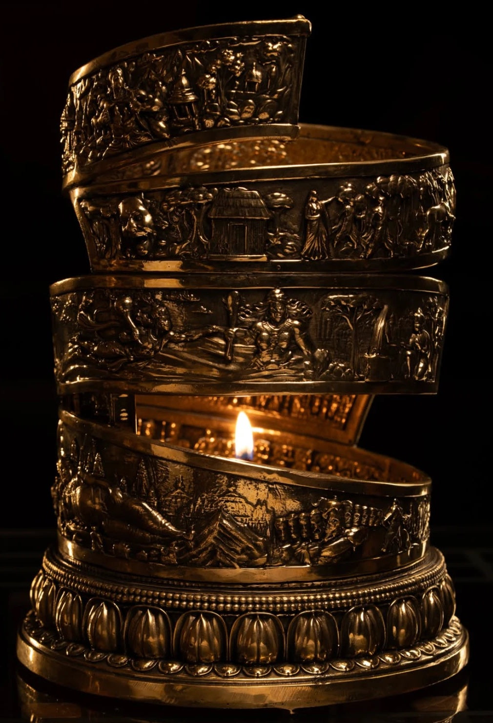 The Ramāgaman lamp lit, its embossed brass spiral rising from a lotus base