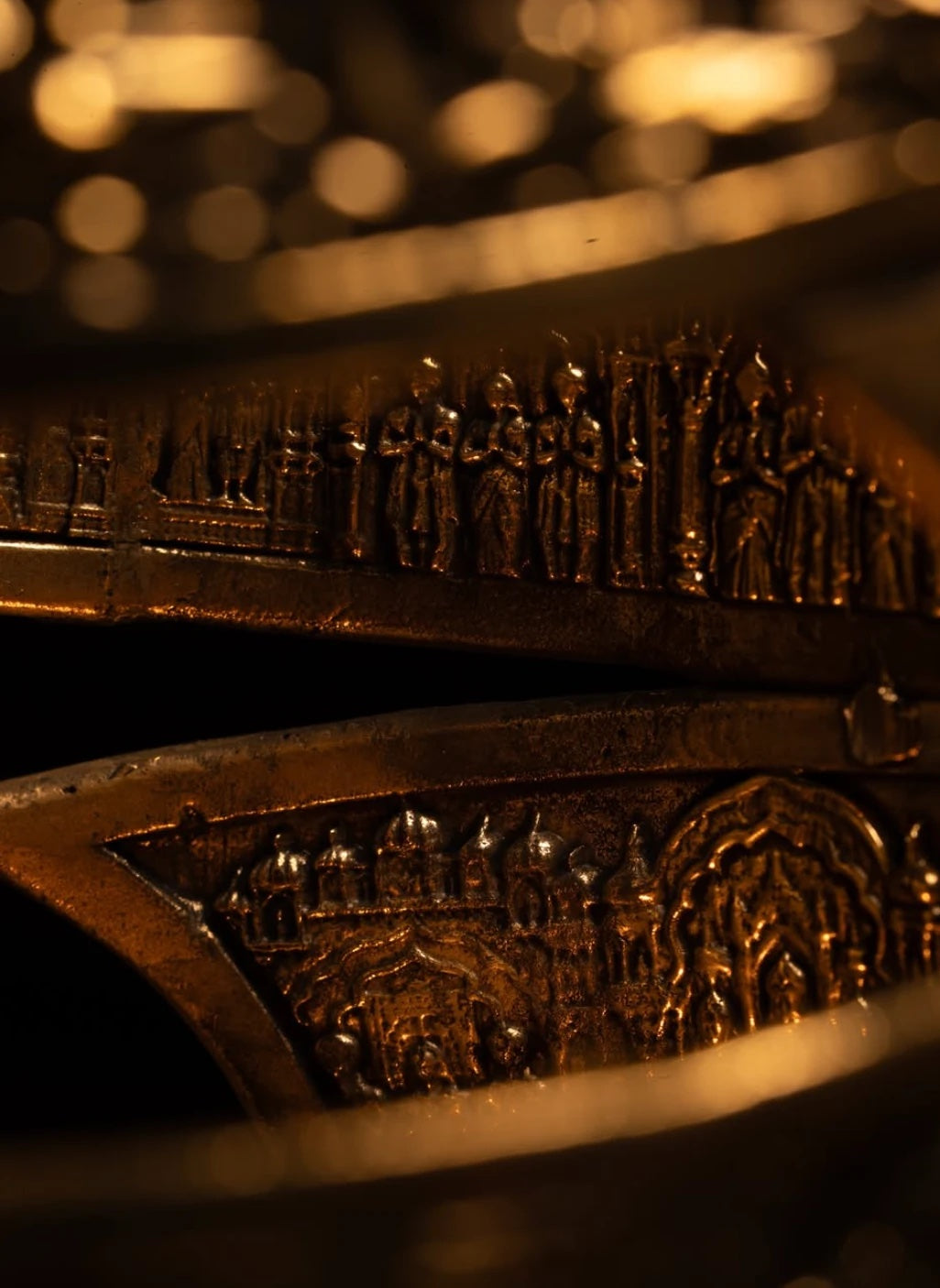 Embossed brass scenes of a city and a royal procession, in warm light