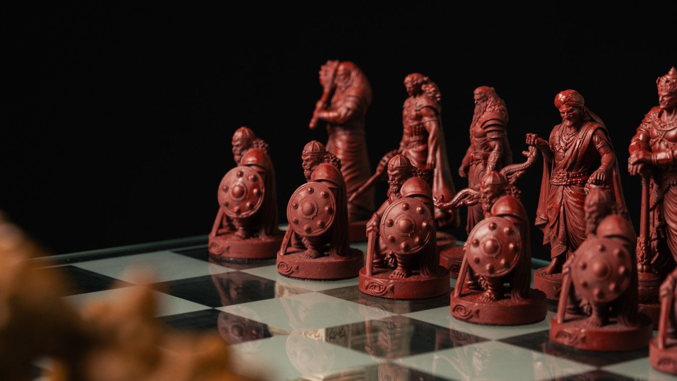 The maroon Kaurav warriors arrayed on the glass board, Pandav pieces soft in the foreground